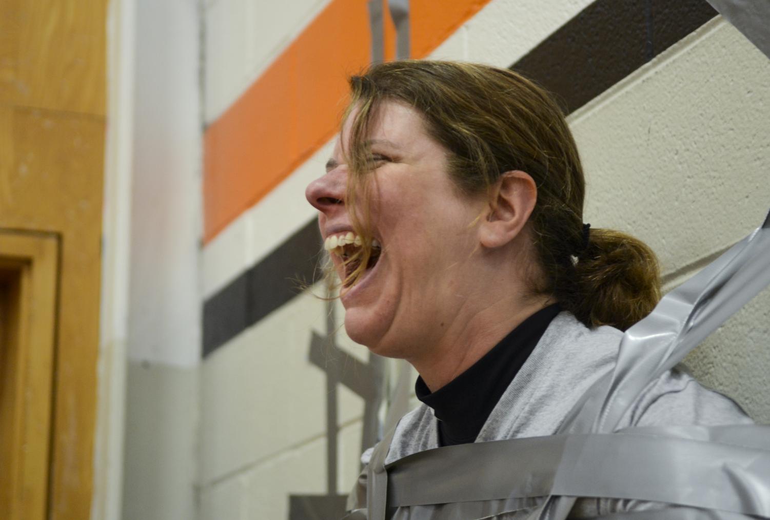 Principal Lisa Gruman hangs from a wall in the Main Gym, Sept. 11 after students taped her there. Taping Gruman to the wall was one of the activities students could participate in as a reward during the first Cougar CORE Day.