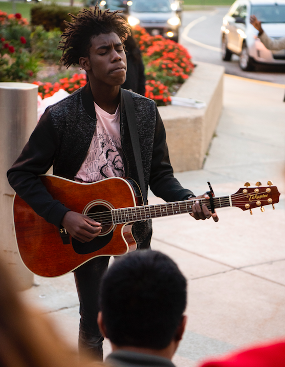 Eyes closed, junior Tre Mutava sings "Reckless Love" by Corey Ausburg while he leads worshup outside the school Oct 3. at the annual See You at The Pole event. Mutava leads worship at City Center Church in the 180 Ministry. "I just enjoyed spending time in God's presence and just getting into worship as we were there at the pole," Mutava said. "It's a way of stepping out as a fellow Christ follower in your school and in front of everyone that walks into the front doors." 