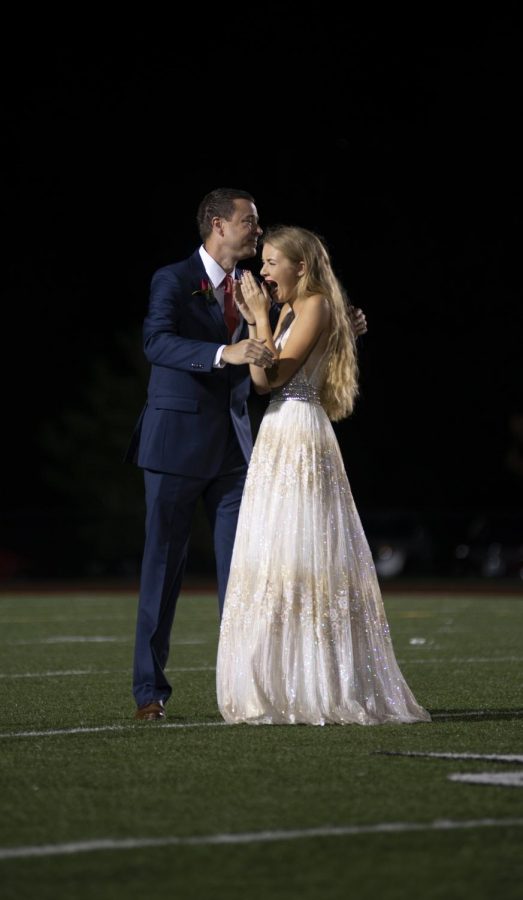 Standing side by side, senior Mabel Anstine and her father Jason react to hearing her announced as 1st runner-up during the Homecoming crowning ceremony Oct. 5 at SM North District Stadium. Anstine was nominated by  the girls' tennis team. "You've watched it happen every year and now it's you," Anstine said. "It was crazy to see everyone watching me being under the lights... and how insane it was to be standing out there with the rest of those girls." 