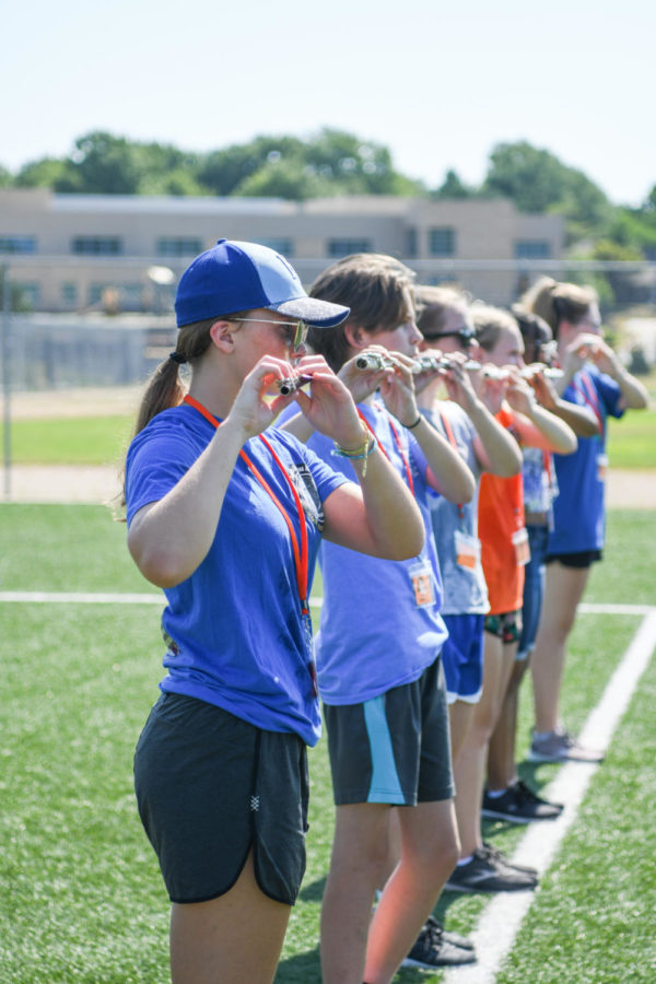 Playing the flute, freshman Amber Quint adjusts her horn angle July 22 on the Northwest football field. Quint adjusts her horn angle to make sure the instrument is horizontal. “At first it was pretty difficult trying to get the spacing down,” Quint said. “That way no one got knocked in the head while marching.” 
