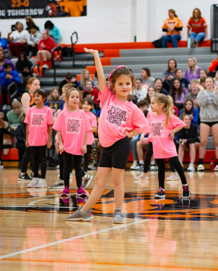 During a halftime performance, kindergartener Juliet Eichman poses for the crowd Jan. 10 in the Main Gym. Eichman was part of the dance clinic ran by the Cougar Classics where they learned a dance to perform at the basketball game. “My favorite part was performing in front of everyone,” Eichman said. “It was also fun to practice with the dance team.”