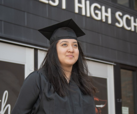 Junior Elaina Hammes wears wa cap and gown Feb. 27 in front of the West entrance.