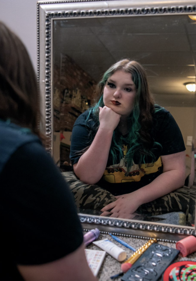With two different personalities represented in her makeup, senior Sophia McCraney looks at herself in the mirror May 1 at her house.