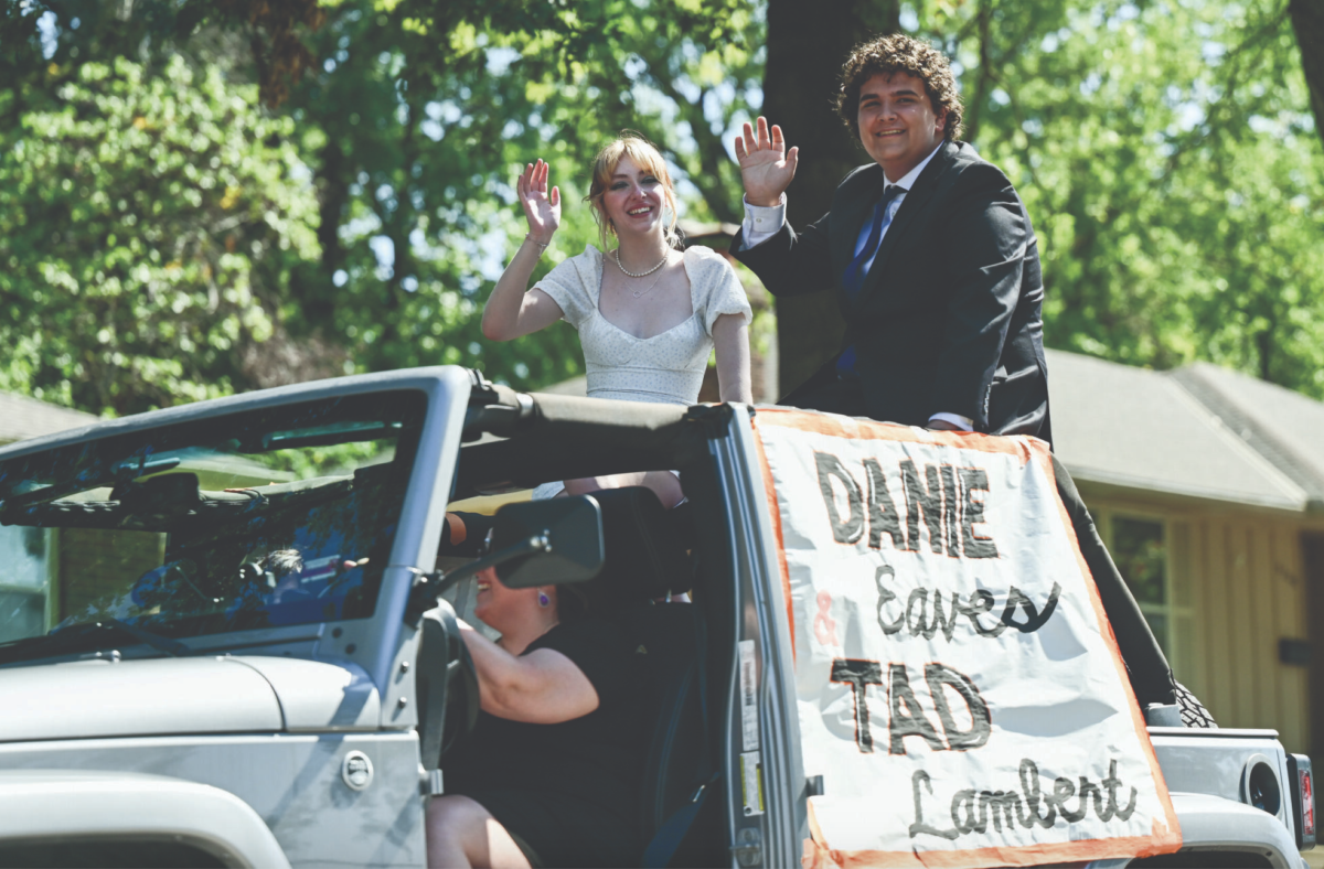 Sitting in a car, seniors Danie Eaves and Tad Lambert wave to the crowd Sept. 28 on Caenen Ave. Eaves and Lambert were voted into court by the senior class. “Getting on court was an incredible experience,” Eaves said. “It was great being able to experience the tradition and community brought along with it.”