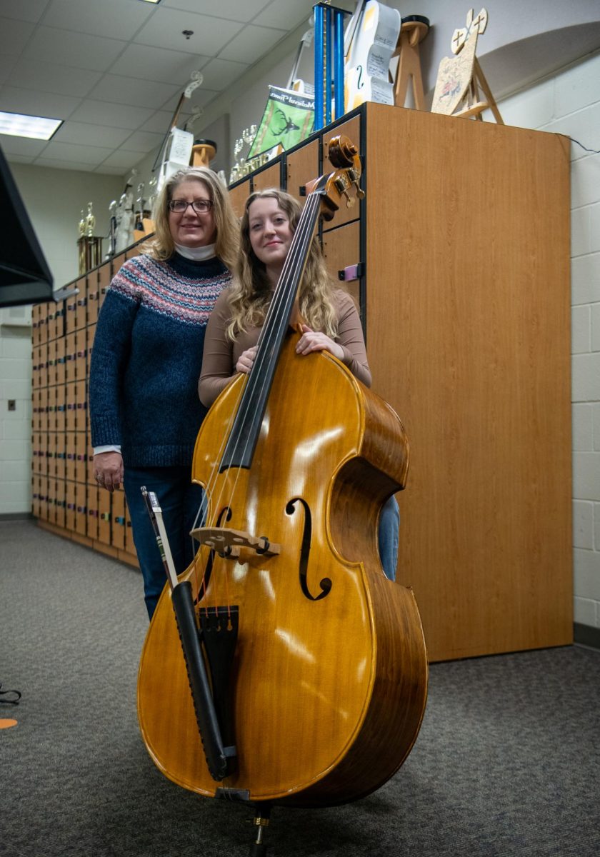 Sophomore Clare O’Malley and her mom stand with her concert Cello Jan. 18 in the Orchestra Room. 
Photo by Sidra Sakati