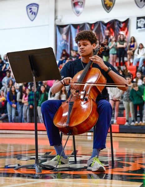 Playing the cello, senior Julian Jones performs at the Black History Month Assembly Feb. 6 in the Main Gym. Jones was playing Saint-Saens Cello Conterto no. 1. “I found it rewarding afterwards that I was able to play pieces on that degree of difficulty in front of about 300+ people,” Jones said. “I was extremely grateful that doing that helped people recognize my talent.” Photo by Ashley Broils

