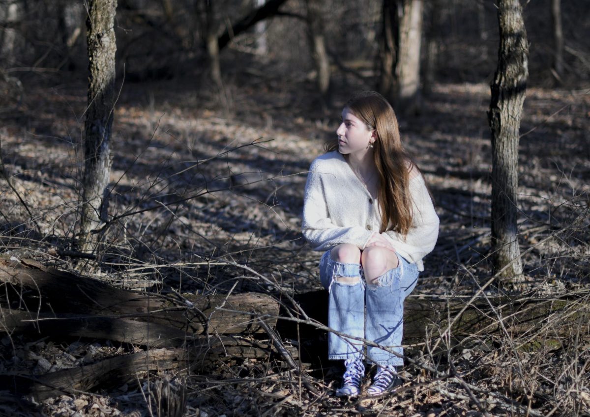After running away from her parents, freshman Emma Wycoff sits on a log Feb. 5 in Shawnee Mission Park.  Cooper Evans