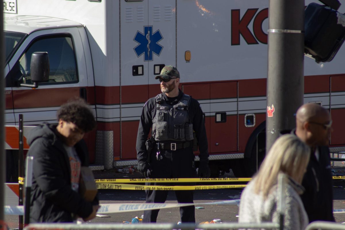 A Kansas City Police Officer stands behind police tape Feb. 14 at Crown Center. Officers surrounded the area after a mass shooting occurred following the Chiefs Super Bowl Parade leaving one dead and over 20 injured. The situation ended in two juveniles being put in custody. Photo by Haylee Bell
