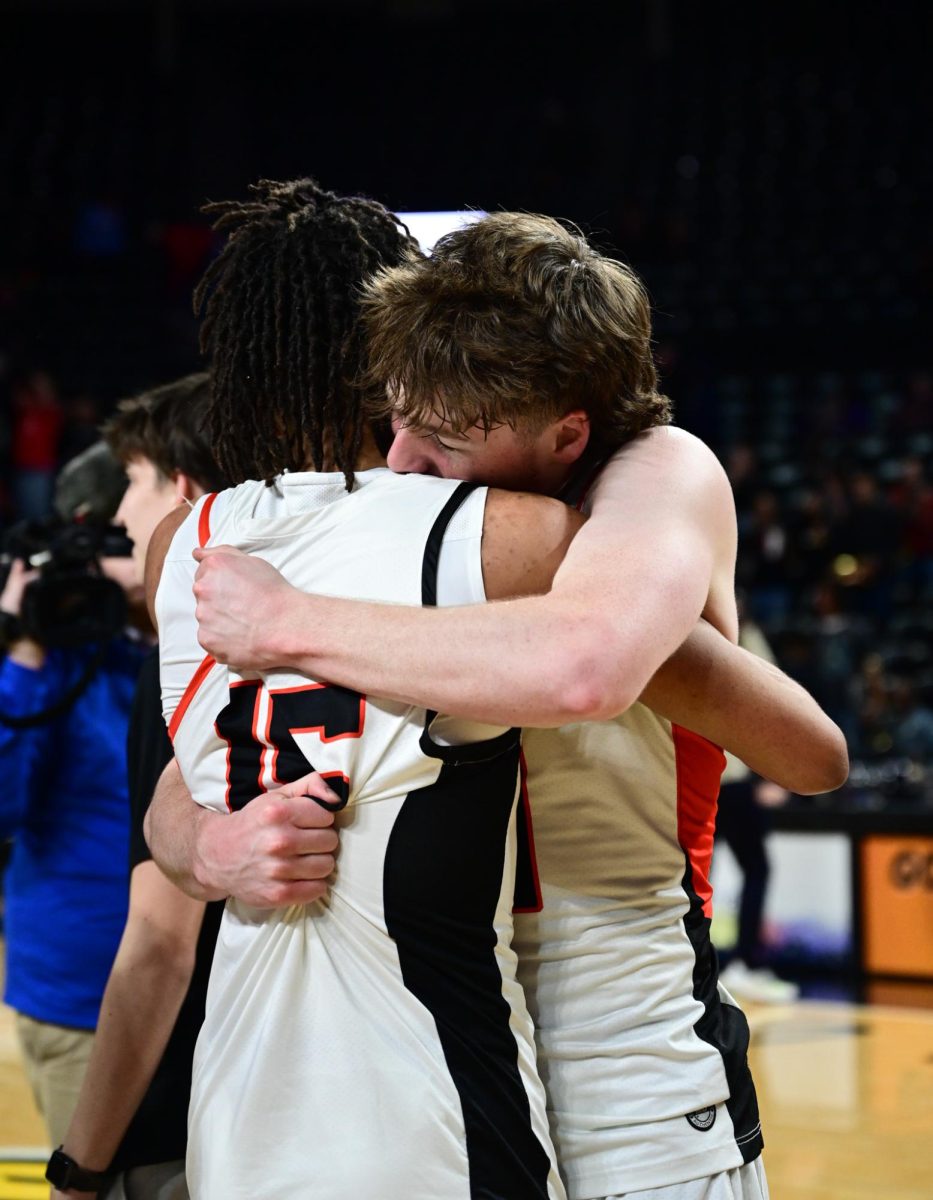 Juniors Van Collins and Aiven Riley hug after winning the state basketball game March 9 at Charles Koch Arena. The boys basketball team finished the season undefeated. “I was just thinking about all the hard work me and my teammates have put in through the year,” Collins said. “To see it come alive and pay off was just amazing.” Photo by Ashley Broils
